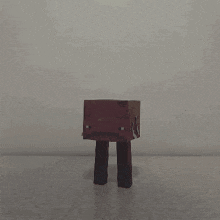 a person 's hand is reaching out towards a cardboard box with a face on it