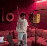 a man wearing headphones is standing in front of a microphone with his arm in the air ..