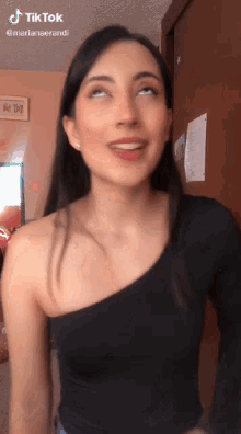 a woman wearing a black one shoulder top looks up at the camera with a tiktok watermark