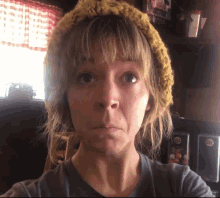 a woman wearing a yellow hat and a gray shirt looks at the camera