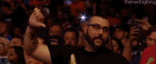 a man in a crowd of people is giving a thumbs up .