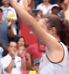 a woman is holding a tennis racquet in the air in front of a crowd .