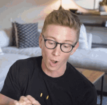 a man wearing glasses and a black shirt with a smiley face on it