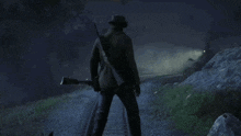 a man in a cowboy hat is standing on a train track holding a gun .