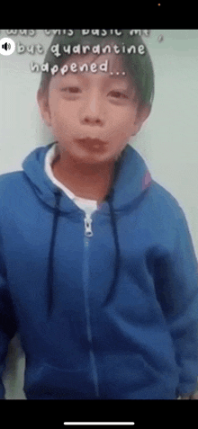 a boy in a blue hoodie is standing in front of a wall .