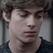 a close up of a young man 's face in a black shirt .