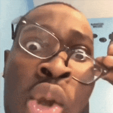 a man wearing glasses is making a funny face with his tongue out .