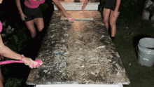 a woman is cleaning a table with a pink brush