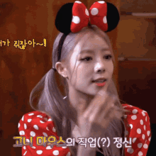 a girl wearing a red and white polka dot dress and a headband with a minnie mouse bow