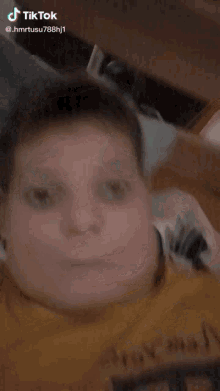 a young boy is laying on a bed with a tiktok watermark on his face
