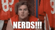 a man in a red jersey is sitting in a locker room with a bunch of jerseys hanging on the wall .