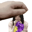 a hand is holding a purple balloon over a woman .