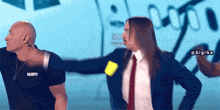 a man wearing a security shirt stands next to a woman in a suit