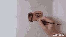 a person is painting a woman 's face with a brush and the words made in animatica on the bottom