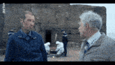 two men talking in front of a building that says arte on the bottom