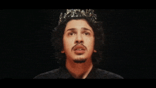 a man wearing a crown on his head looks at the camera