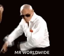 a man wearing sunglasses and a white shirt is sitting on a chair and says `` mr worldwide '' .