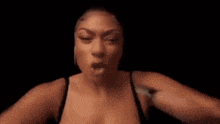 a woman in a black bra and earrings is making a funny face .
