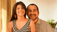 a man and a woman are posing for a picture and the woman is wearing a striped tank top