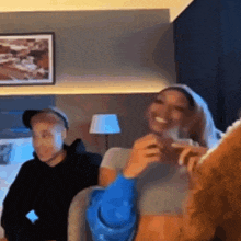 a man and a woman are sitting on a couch in a room laughing .