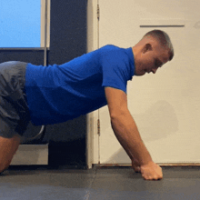 a man in a blue shirt and shorts is doing push ups