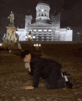 a man kneeling down in front of a large building