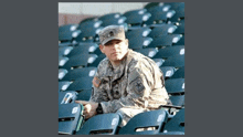 a man in a military uniform is sitting in a stadium seat