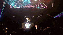 a dj stands in front of a large screen that says ' hatsune miku live ' on it
