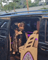 a woman is getting out of a car with a purple light behind her