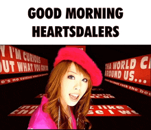 a woman wearing a pink beret is standing in front of a sign that says " good morning heartsdalers "