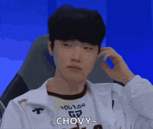 a man is sitting in a chair with his hand on his ear and making a face .