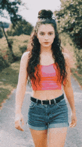 a woman with curly hair is walking down a road