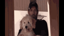 a man holding a puppy wearing a baseball cap with the letter a on it