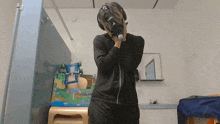 a person wearing a gas mask is standing in front of a toy train set