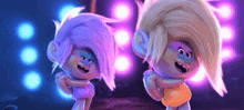 a couple of trolls are dancing together on a stage in front of a crowd .