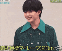 a young man wearing a green sweater and a green collar is smiling