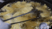 a pan of food is being cooked with tongs and a thermometer in it .