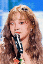 a woman with a flower in her hair is singing into a microphone