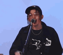 a man with dreadlocks and glasses is singing into a microphone .