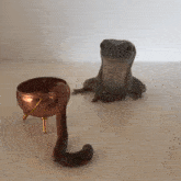 a frog is sitting next to a snake and a copper pot
