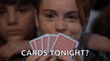 a woman is holding a bunch of playing cards in front of her face and says `` cards tonight ? ''