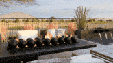 a table with black balls on it with a view of a mountain in the background