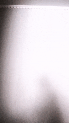 a black and white photo of a wall with a light shining through it