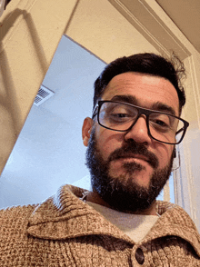 a man with glasses and a beard is standing in a doorway
