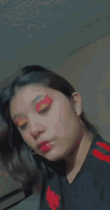a close up of a woman 's face with red and yellow eyeshadow .