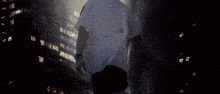 a man in a white t-shirt is standing in front of a building