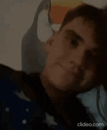 a young man is making a funny face while laying in bed with his finger on his nose .