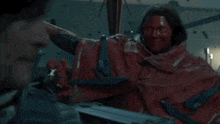 a man with red paint on his face and a red cape