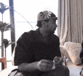 a man wearing a hat with a sun on it is sitting on a couch