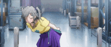 a girl in a yellow shirt and purple skirt stands in a hallway
